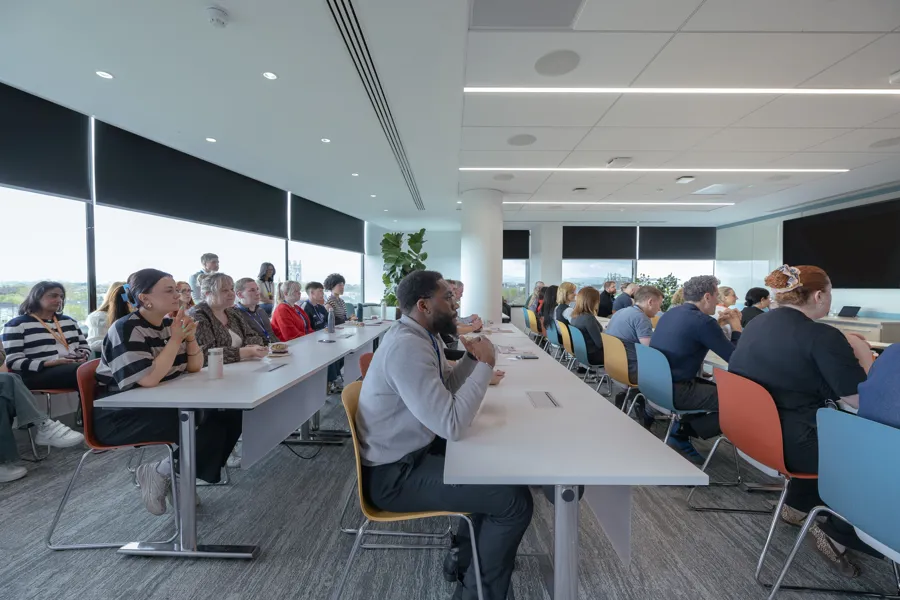 A diverse group of people seated in a modern conference room during a presentation
