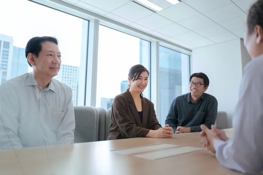 A group of four people engaged in a discussion around a conference table