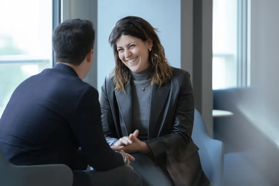 Two people engaged in a conversation while seated in a modern interior setting