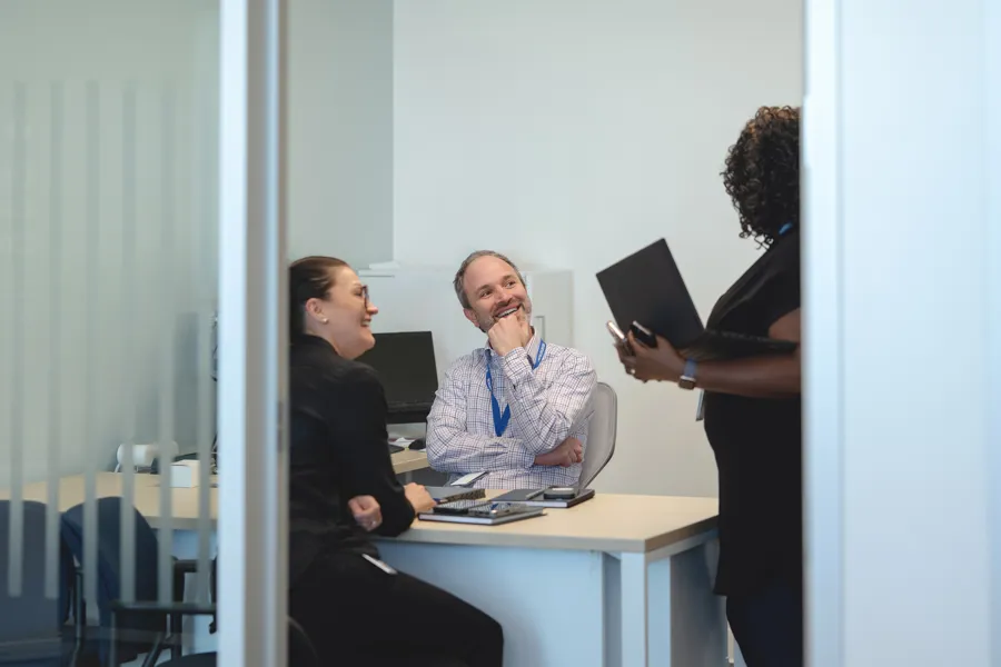 Three colleagues engaged in a discussion in an office setting